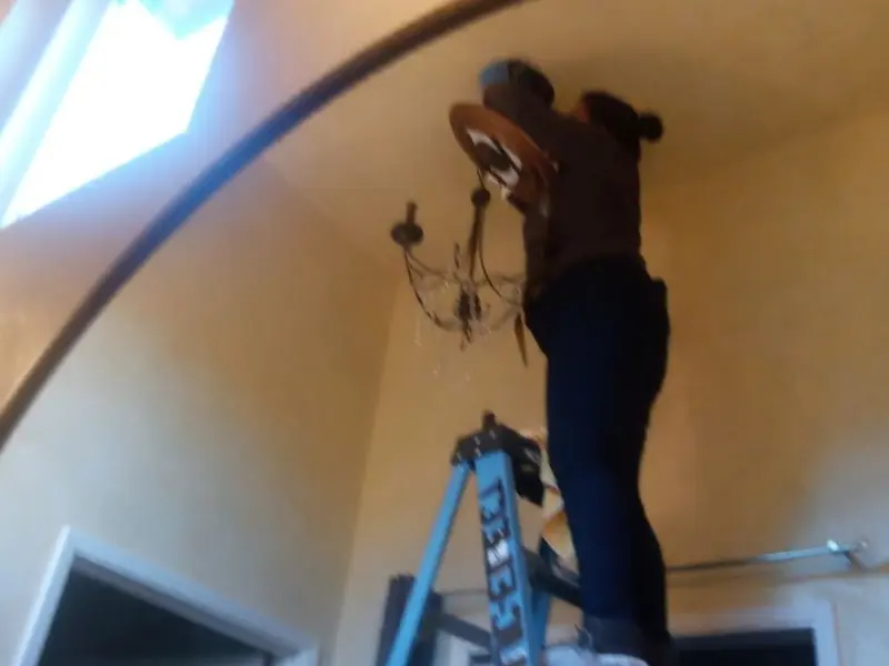 Electrician installing a chandelier in a Verde Village residence